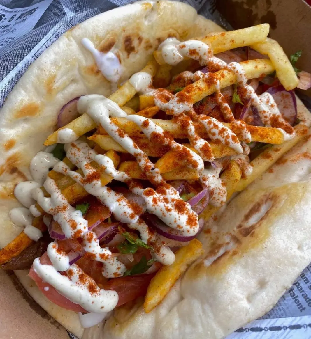 A Greek Street hot pita loaded with meat, chips, tomato, onion and house-made sauce