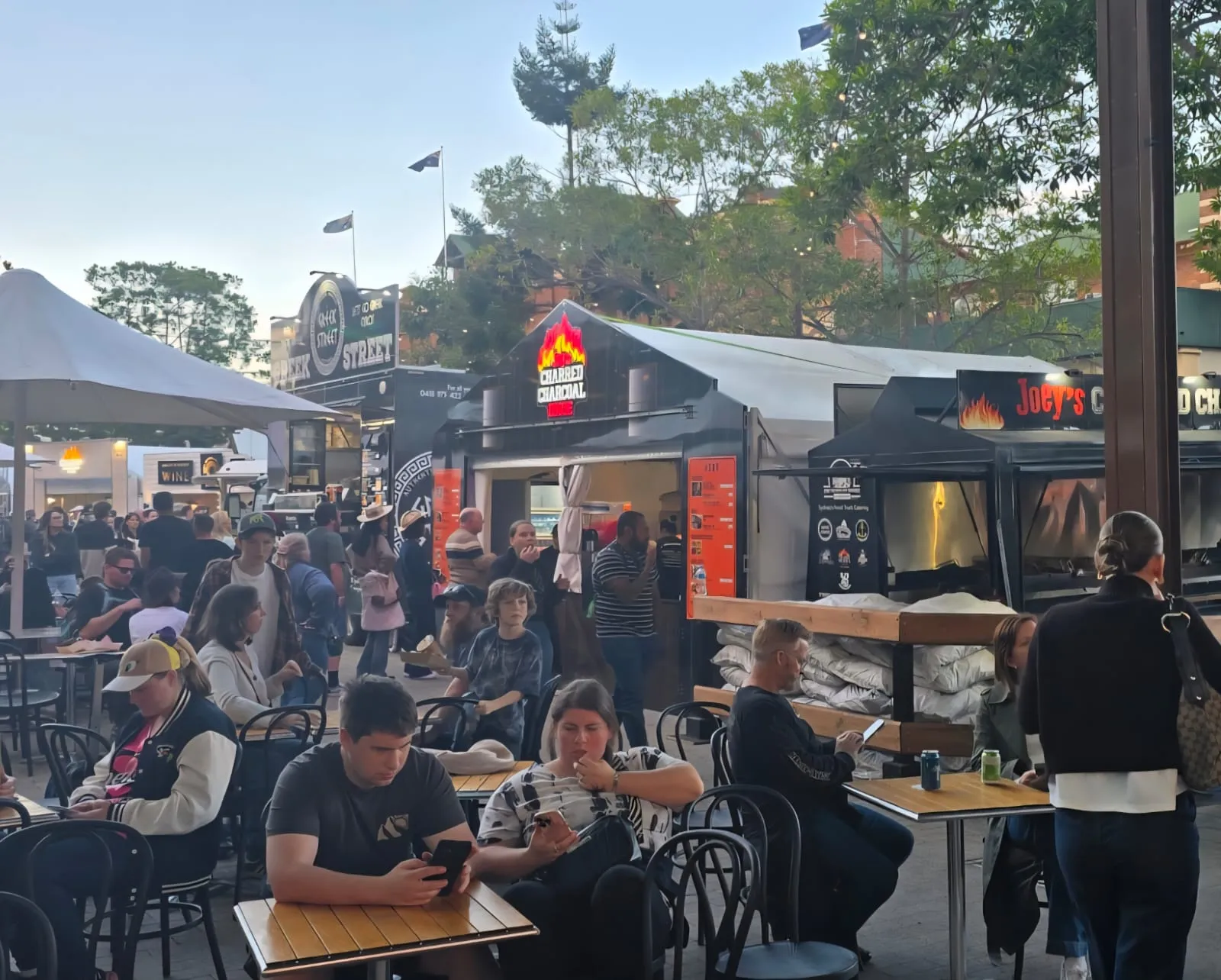 Guests dining outside Joey's Charred Charcoal House and Greek Street at dusk