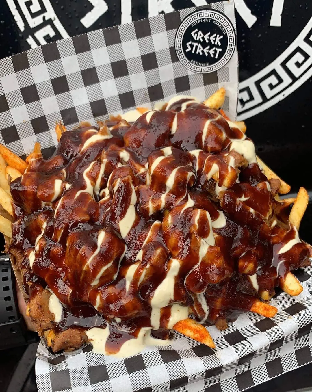 A Greek Street snack pack topped with barbecue and garlic sauce