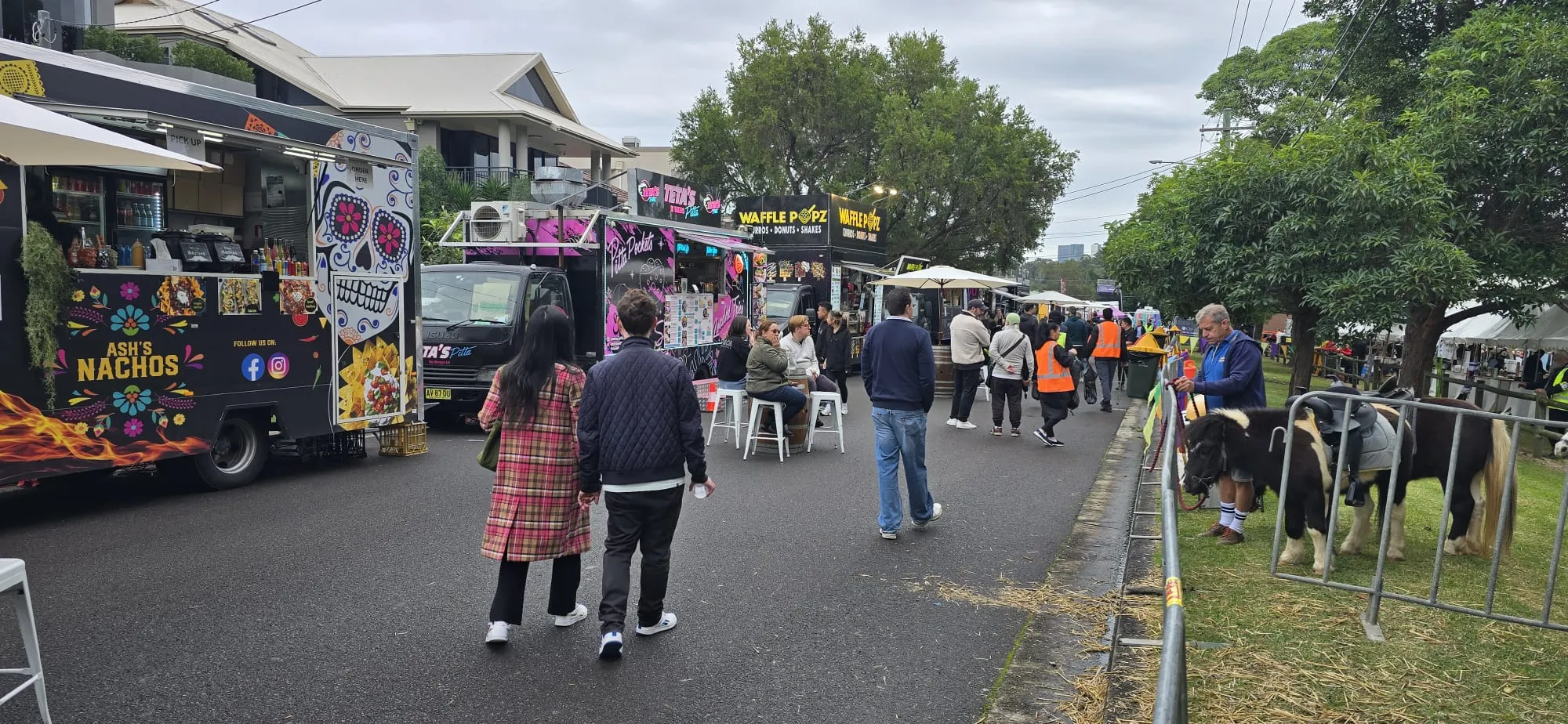 A street food festival lined with food trucks, with guests walking between the stalls